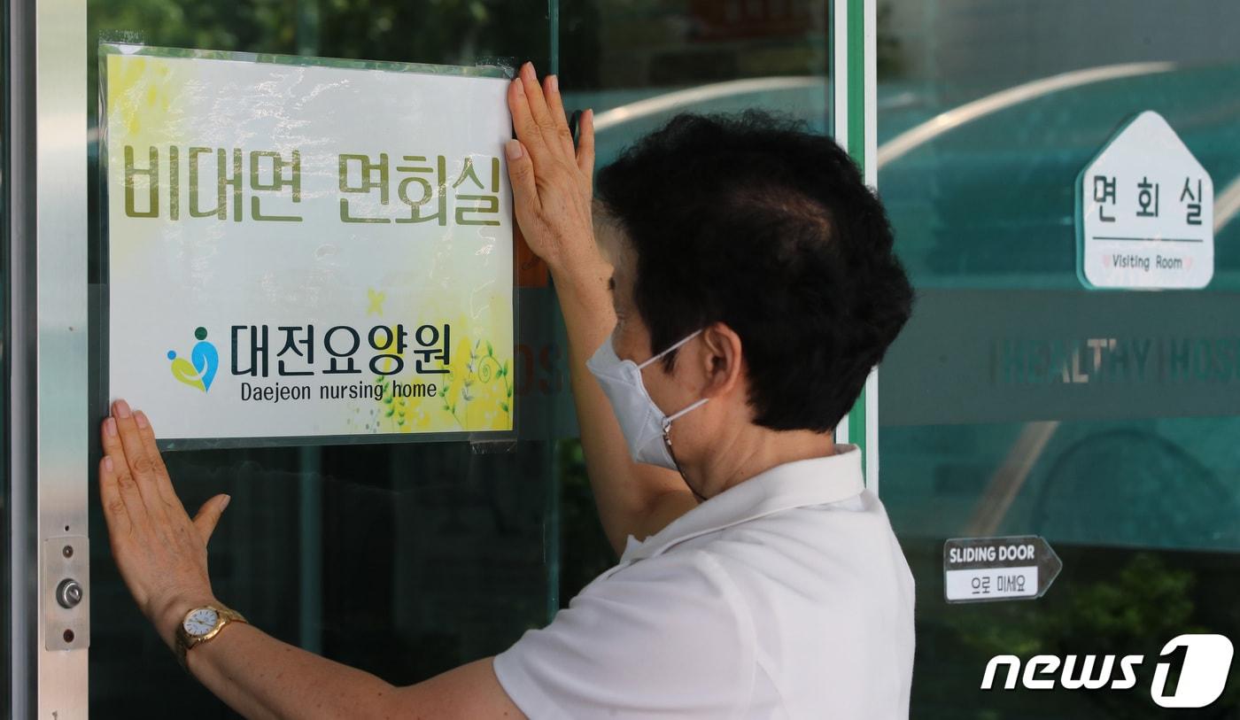 본문 이미지 - 20일 오후 대전 서구 대전요양원에서 직원이 비접촉면회실 안내 문구를 붙이고 있다. /뉴스1 ⓒ News1 김기태 기자