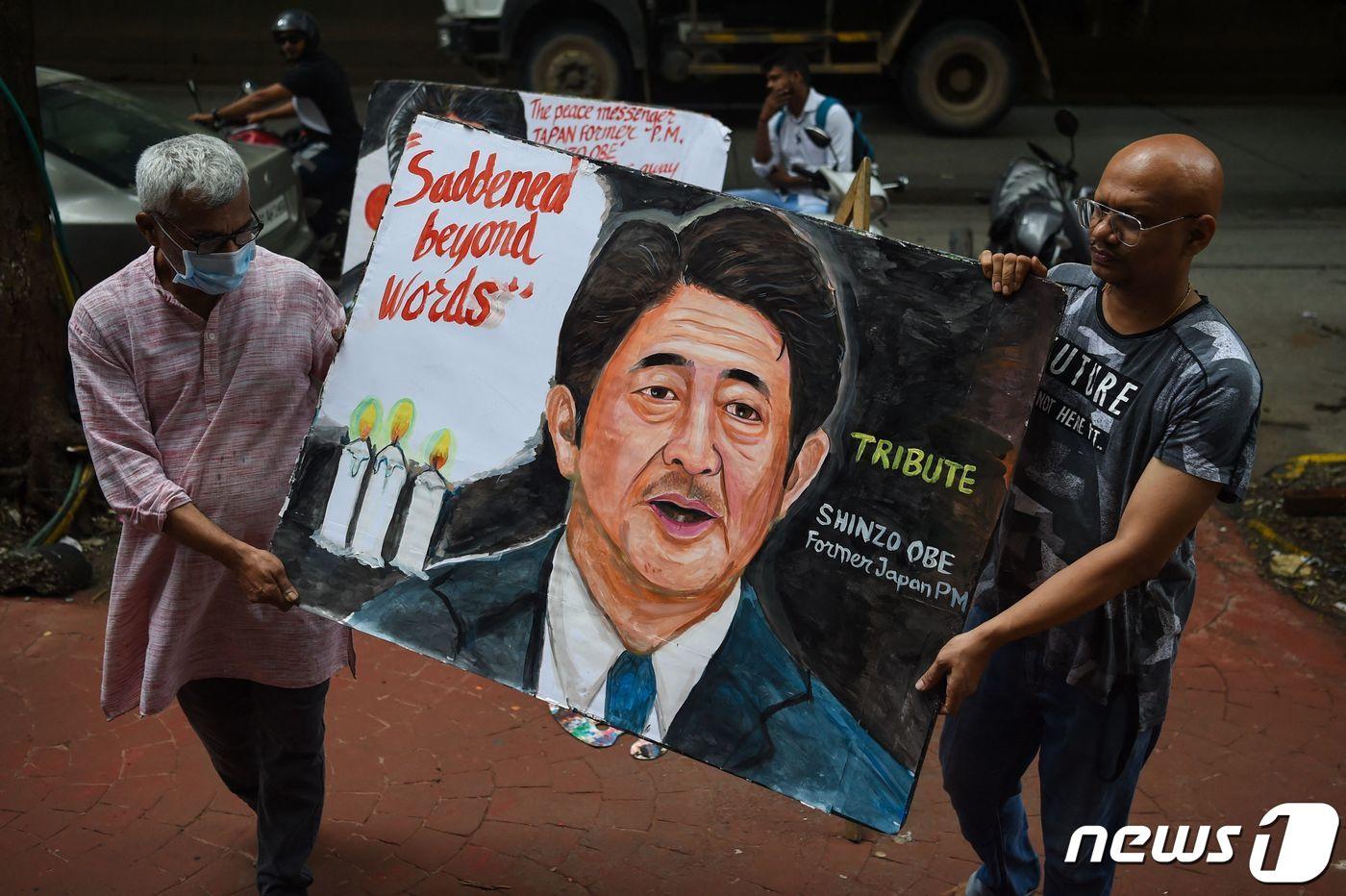 본문 이미지 - 아베 신조 전 일본 총리가 선거 유세중 총에 맞고 숨진 다음날인 8일(현지시간) 인도 뭄바이에서 예술가들이 아베 총리의 그림을 들고 이동하고 있다. ⓒ AFP=뉴스1 ⓒ News1 이성철 기자