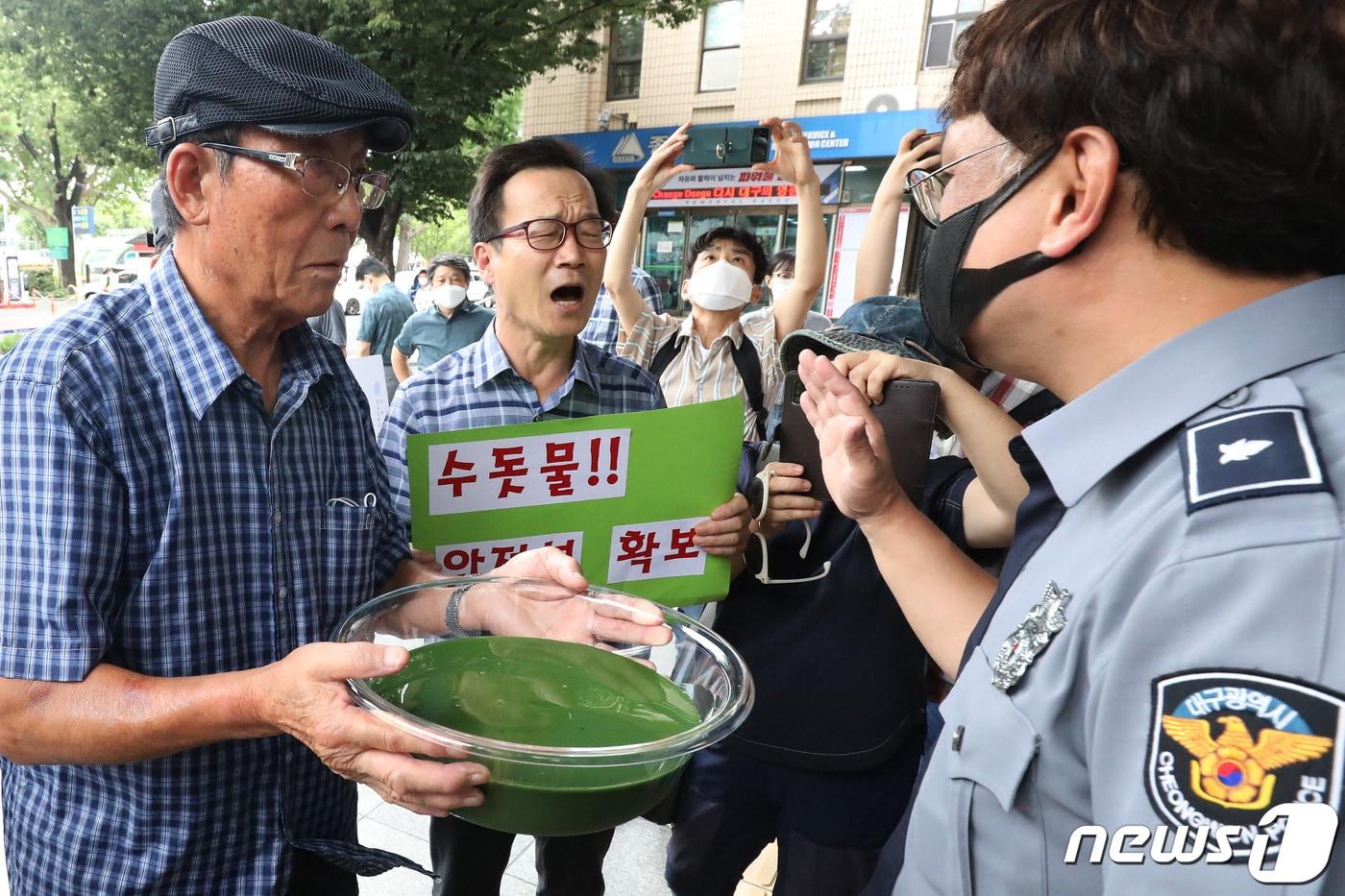 본문 이미지 - 낙동강네트워크·낙동강대구경북네트워크 등 영남권 환경단체 회원들이 달성군 매곡정수장 인근 낙동강에서 퍼온 물을 투명 용기에 따른 뒤 대구시장 항의방문과 서한문 전달을 시도하며 청사 정문 앞에서 청원경찰과 대치하고 있다. 2022.8.1/뉴스1 ⓒ News1 공정식 기자