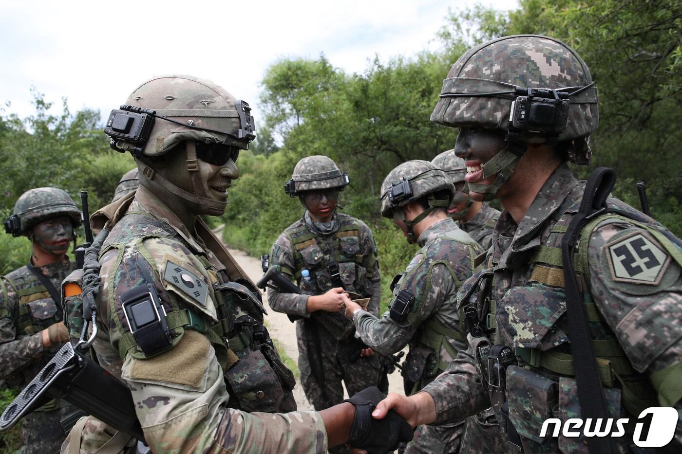 본문 이미지 - 육군25보병사단 해룡여단과 한미연합사단 순환배치여단 장병들이 24일 강원 인제군 육군과학화전투훈련단(KCTC)에서 전개한 22-7차 전투훈련에서 태극기와 성조기를 바꿔 달고 악수하고 있다. (국방일보 제공) 2022.8.24/뉴스1