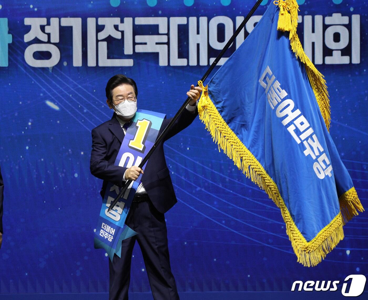 본문 이미지 - 이재명 더불어민주당 새 당대표가 28일 오후 서울 송파구 올림픽체조경기장 KSPO돔에서 열린 제5차 정기전국대의원대회에서 당기를 전달받고 흔들고 있다. (공동취재) 2022.8.28/뉴스1 ⓒ News1 허경 기자