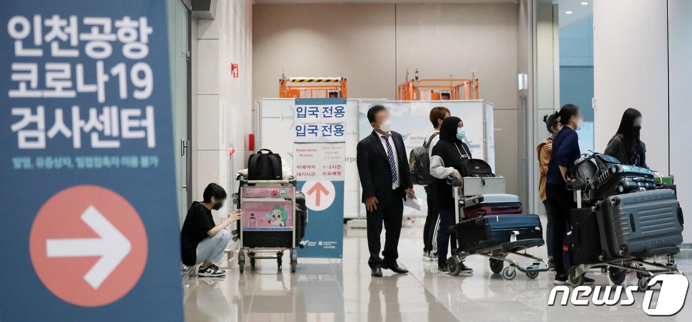 본문 이미지 - 인천국제공항 제2터미널에 마련된 코로나19 선별검사소에서 해외에서 입국한 여행객들이 검사 접수를 하기 앞서 짐을 보관하고 있다.ⓒ News1 