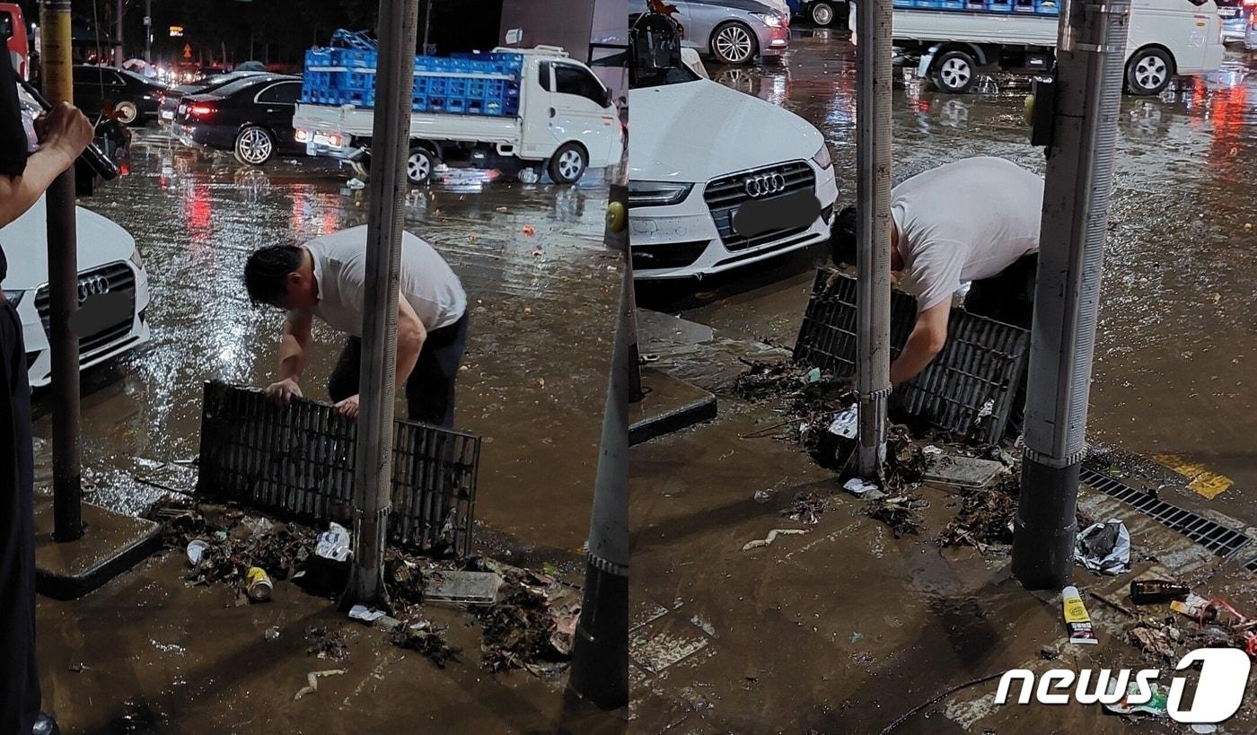 서울 강남역에서 맨손으로 배수구를 막은 쓰레기를 치우는 남성 시민. (온라인 커뮤니티 갈무리) ⓒ 뉴스1