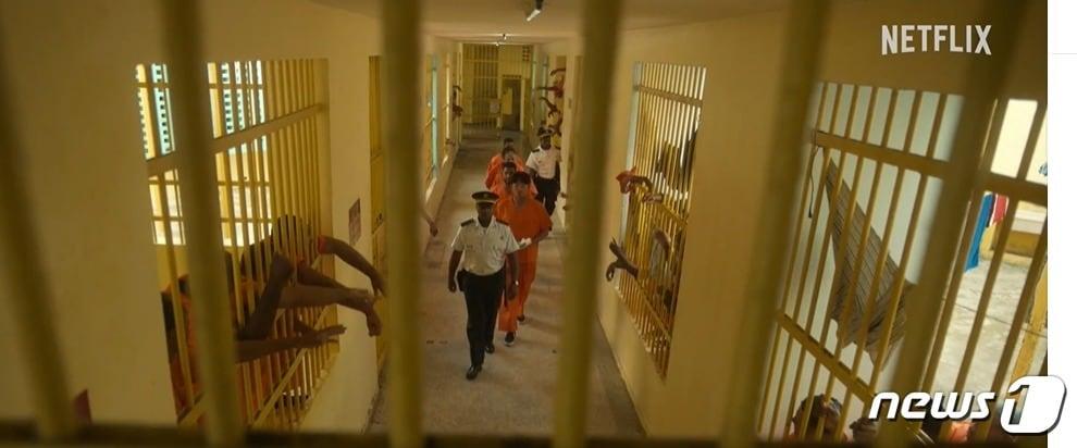 본문 이미지 - 넷플리스 드라마 '수리남'에서 주인공 강인구(하정우)가 음모에 말려 교도서에 수감되는 장면. 실제 교도소에서 재소자들을 출연시켜 사실적으로 찍었다. (수리만 공식 예고편 갈무리) ⓒ 뉴스1 