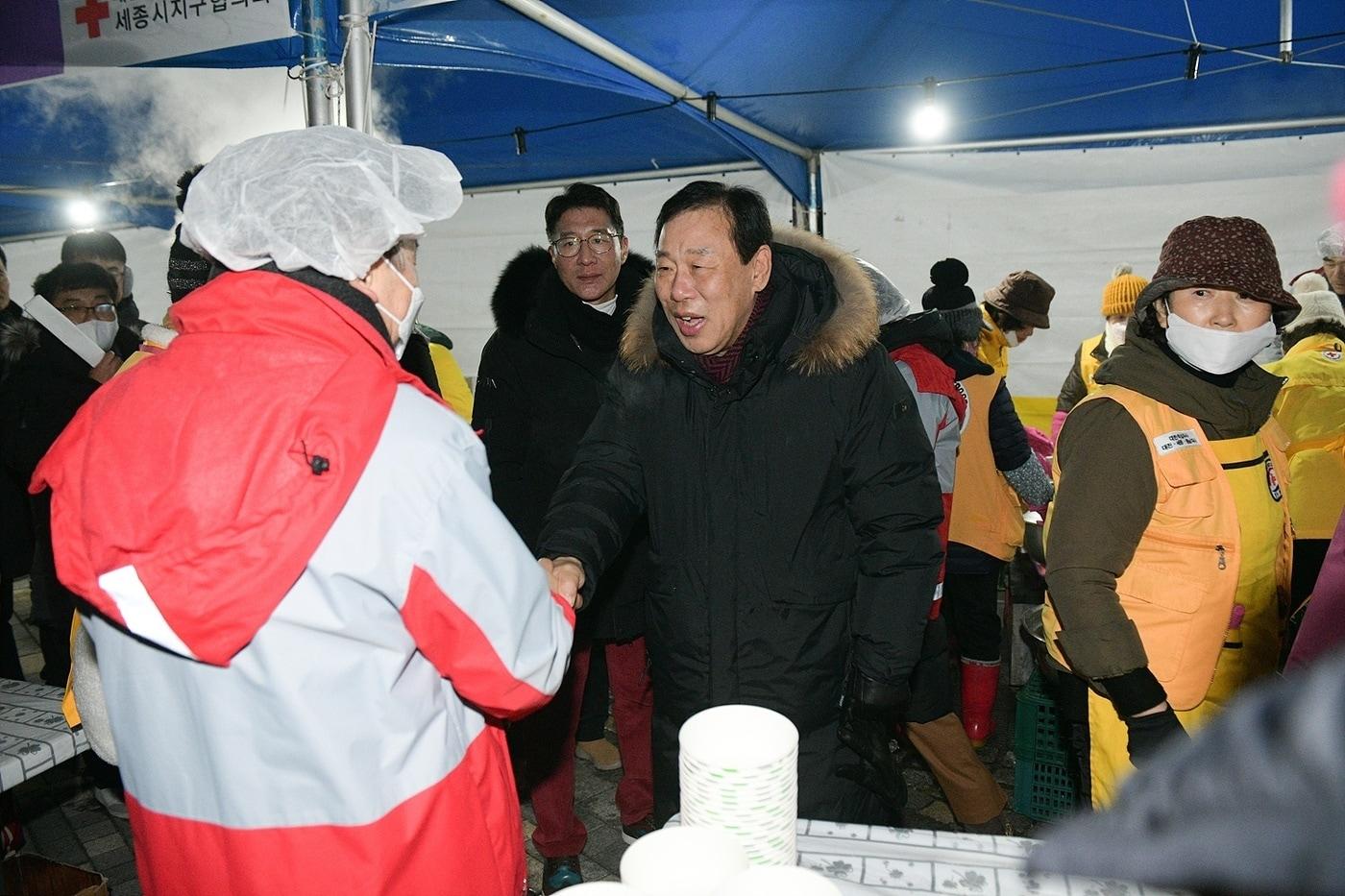 본문 이미지 - 최민호 세종시장이 1일 호수공원에서 열린 해맞이 행사에서 떡국나눔 봉사를 하는 자원봉사자와 악수를 나누고 있다. (세종시 제공) / 뉴스1 