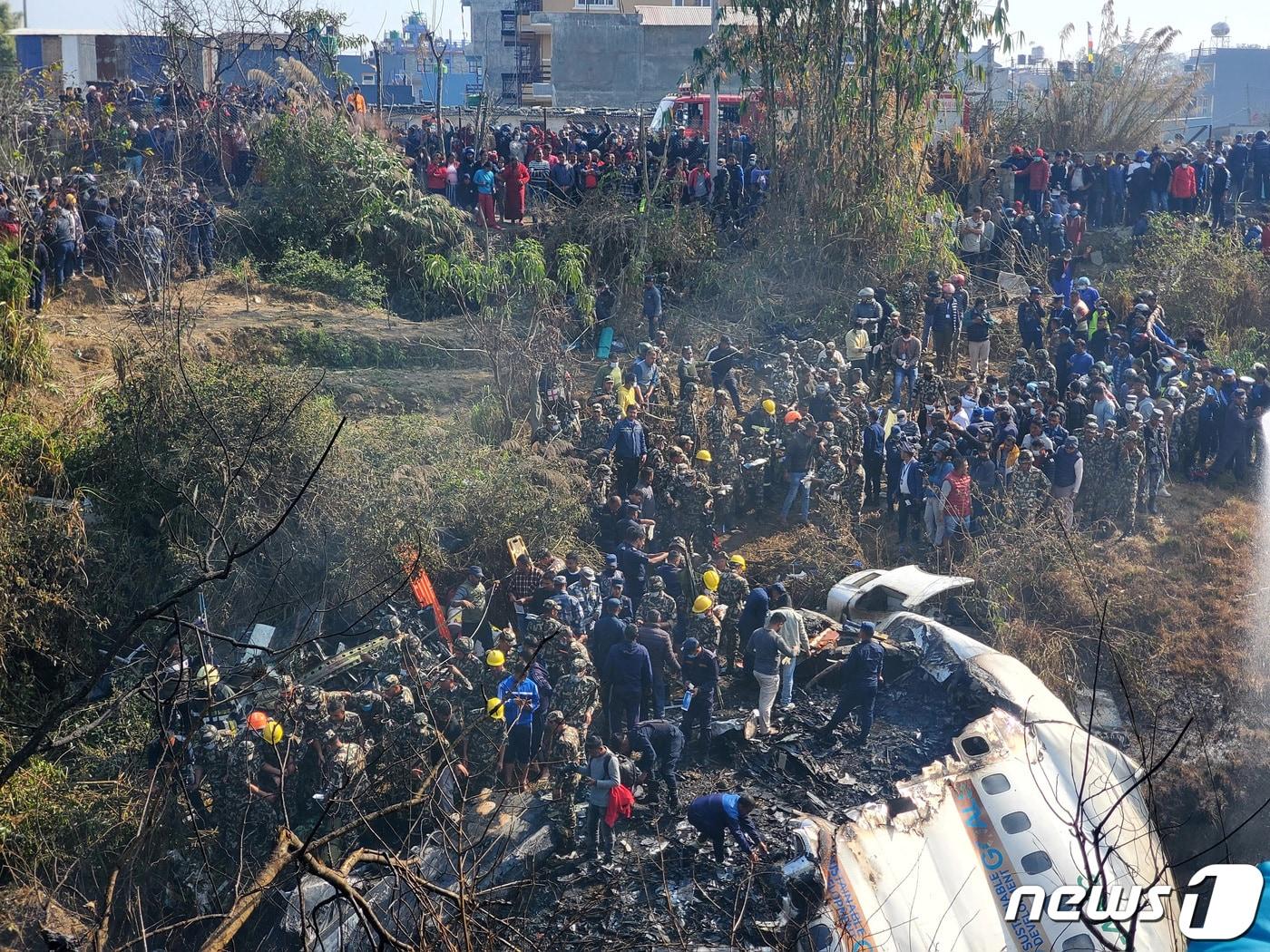 본문 이미지 - 15일(현지시간) 네팔 포카라에서 발생한 비행기 추락 사고 현장. 파손된 기체 주위로 사람들이 모여들어 수습 작업에 한창이다. ⓒ 로이터=뉴스1 ⓒ News1 권진영 기자