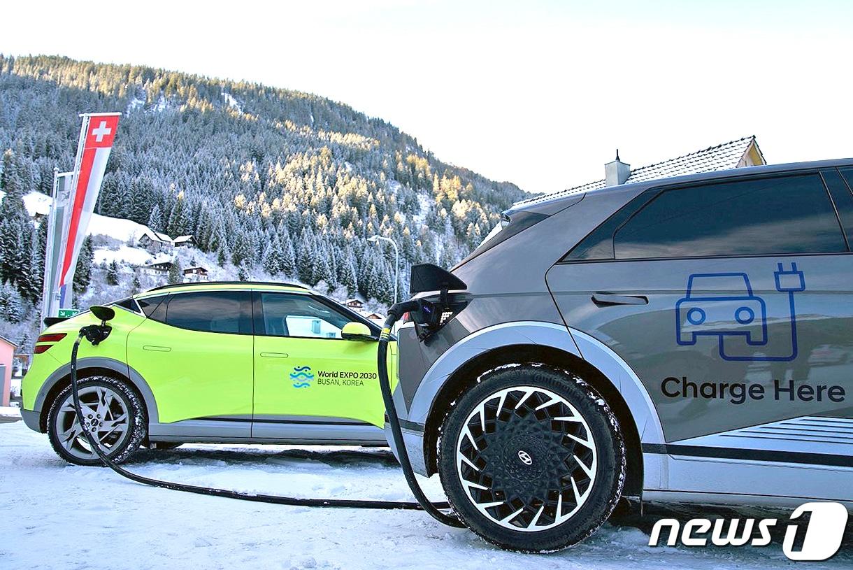 본문 이미지 - 지난 1월 현대자동차그룹은 세계경제포럼이 열리는 스위스 다보스에서 2030 부산세계박람회 홍보 문구가 랩핑 된 차량 58대를 운영했다. 사진은 다보스 인근에서 제네시스 GV60(왼쪽)를 현대차 아이오닉 5에 연결한 뒤 V2L 기술로 충전 중인 모습. (현대자동차그룹 제공) 2023.1.16/뉴스1