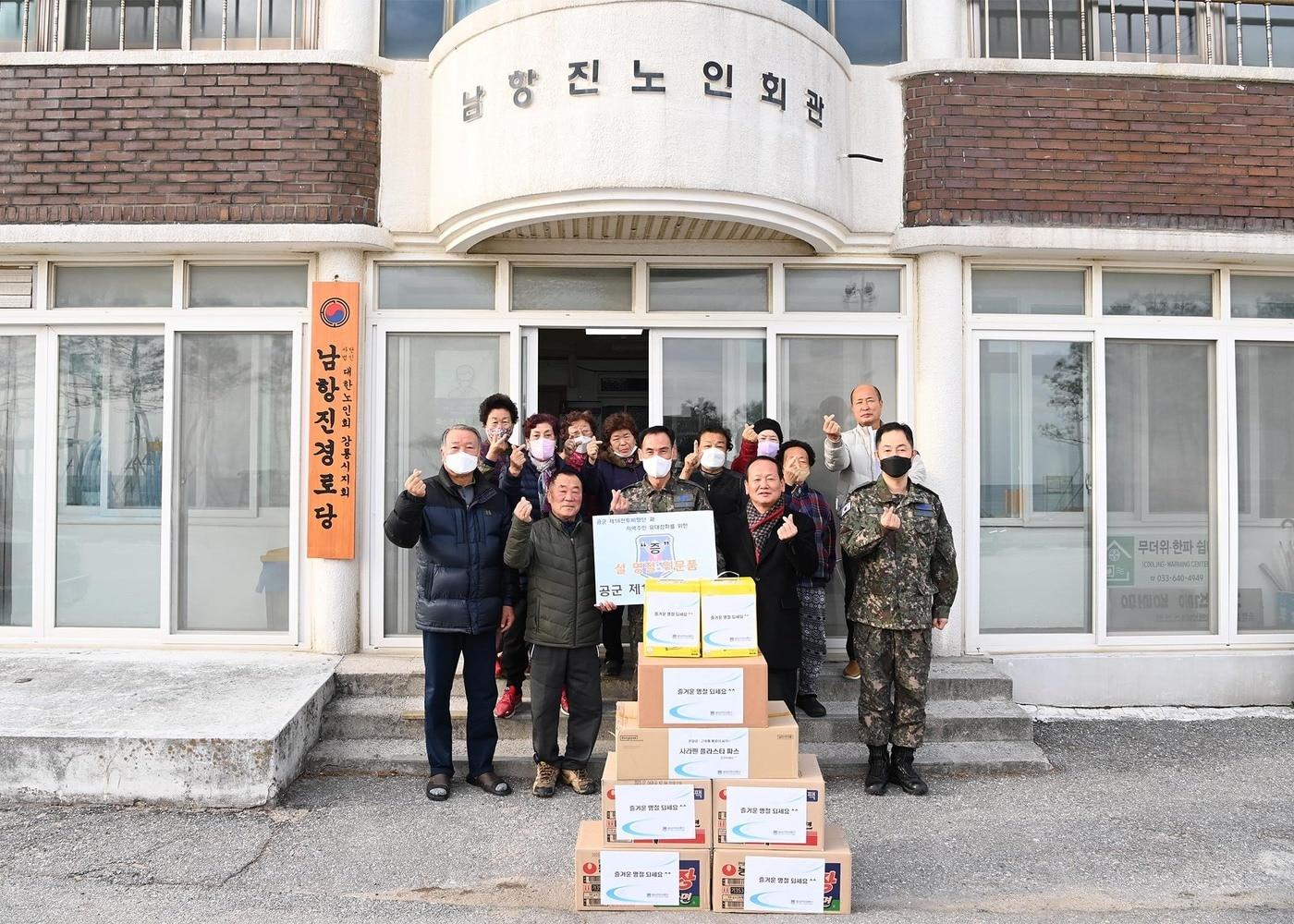 본문 이미지 - 공군 제18전투비행단 오홍균 단장(가운데)이 부대 인근 남항진동 주민들에게 위문품을 전달하며 기념 촬영을 하고 있다.(공군 제공)