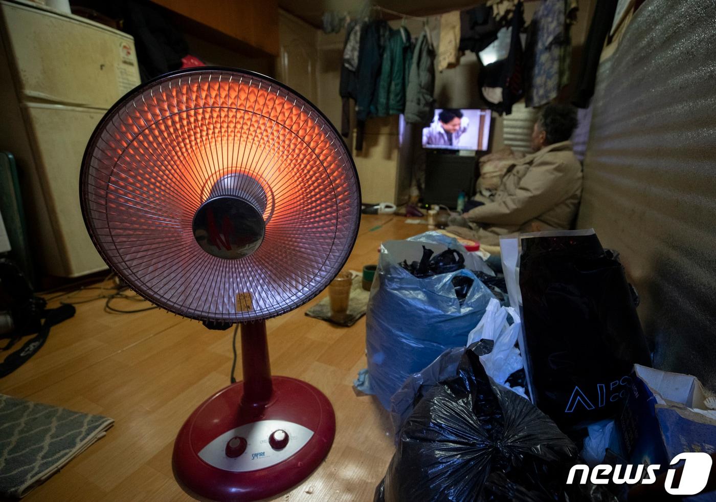 본문 이미지 - 올겨울 가장 강력한 추위가 찾아온 25일 오전 서울 용산구 동자동 쪽방촌에 거주하는 한 노인이 온열기기 하나에 의지해 추위를 견디고 있다. 2023.1.25/뉴스1 ⓒ News1 신웅수 기자