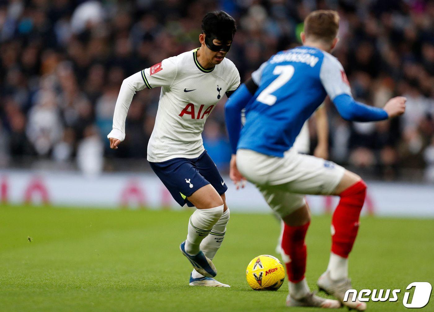 본문 이미지 - 토트넘의 손흥민이 7일 (현지시간) 런던의 토트넘 홋스퍼 스타디움에서 열린 포츠머스와의 FA컵 경기에 마스크를 쓰고 출전해 상대 선수 잭 스완슨과 볼을 다투고 있다. ⓒ AFP=뉴스1 