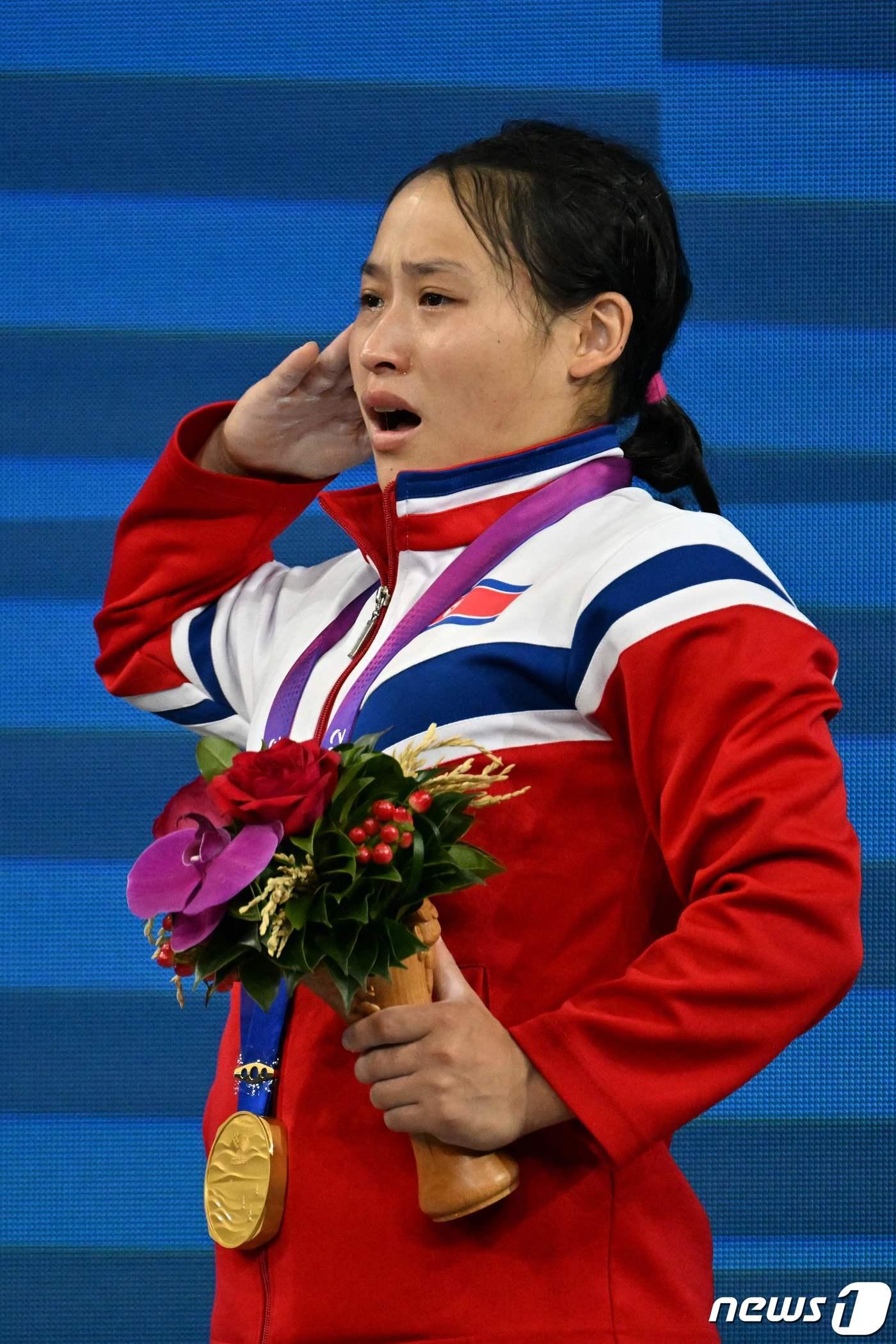 본문 이미지 - 북한 리성금이 9월30일 열린 2022 항저우 아시안게임 역도 여자 49㎏급에서 우승한 뒤 시상대에서 거수경례를 하고 있다. ⓒ AFP=뉴스1