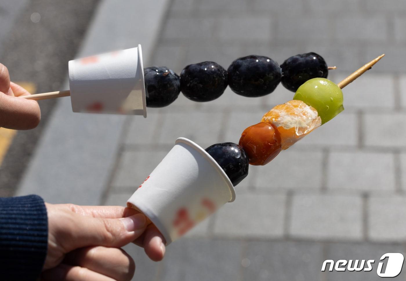 본문 이미지 - 10일 오후 서울시내 거리에서 시민들이 탕후루를 들어보이고 있다. 국회 보건복지위원회는 오는 12일 국정감사에 탕후르 프랜차이즈 운영업체 대표를 증인으로 불러 청소년의 건강권 문제를 질의한다. 2023.10.10/뉴스1 ⓒ News1 이재명 기자