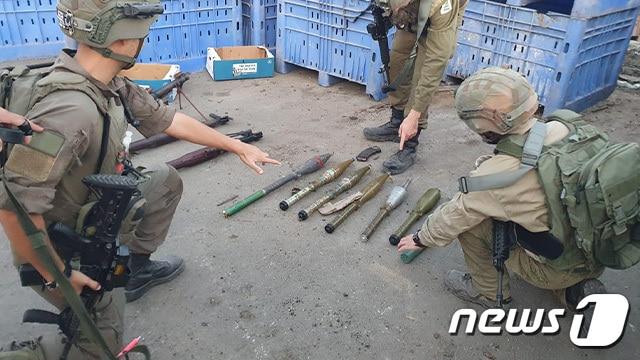 본문 이미지 - 이스라엘군(IDF)이 하마스로부터 압수한 무기들을 공개했다. 왼쪽 장병이 손가락으로 가리키는 무기가 북한제 F-7 무기로 추정되고 있다.(IDF 홈페이지) 