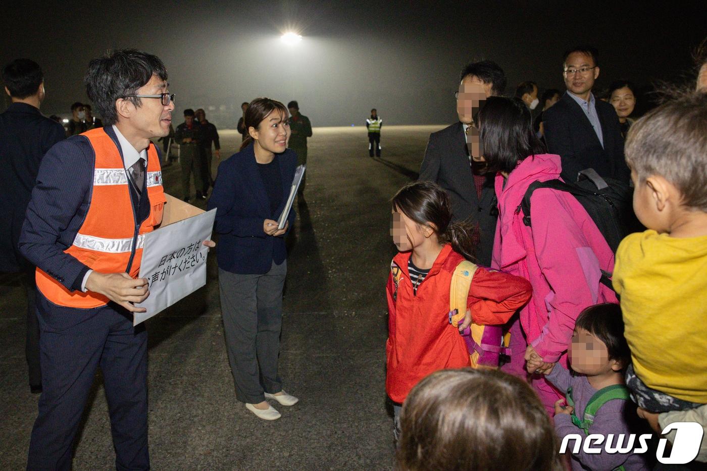 본문 이미지 - 14일 밤 이스라엘에서 출발해 경기 성남 서울공항에 도착한 일본인에게 주한일본대사관 직원이 수속 안내를 하고 있다. 구조 인원은 우리 국민 163명과 일본인 51명, 싱가포르인 6명 등 총220이다. 2023.10.15/뉴스1 ⓒ News1 사진공동취재단