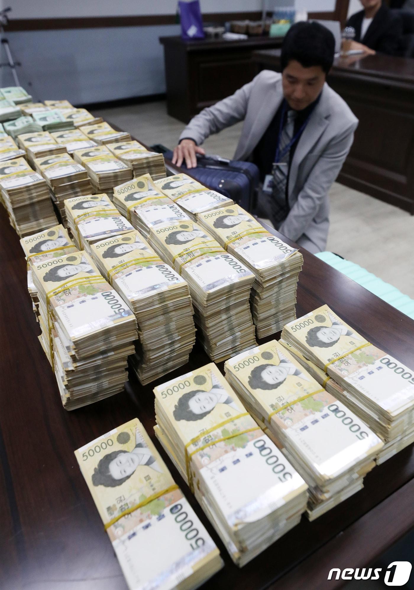 본문 이미지 - 2023년 10월 서울 강북경찰서에서 경찰이 국내에서 가상자산을 매수 후 해외 거래소에서 팔아 수백억원의 자금을 빼돌린 혐의를 받는 국제 환치기 범죄조직으로부터 압수한 현금 및 물품을 정리하고 있다.  2023.10.23 ⓒ 뉴스1 이승배 기자