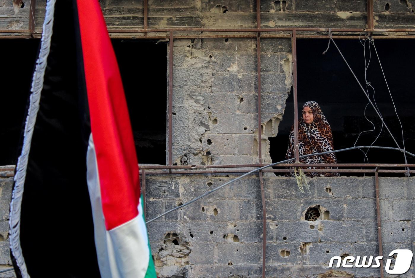 시리아 수도 다마스쿠스의 한 손상된 건물에서 한 여성이 친팔레스타인 시위 장면을 내다보고 있다. 2023.10.20 ⓒ 로이터=뉴스1 ⓒ News1 강민경 기자