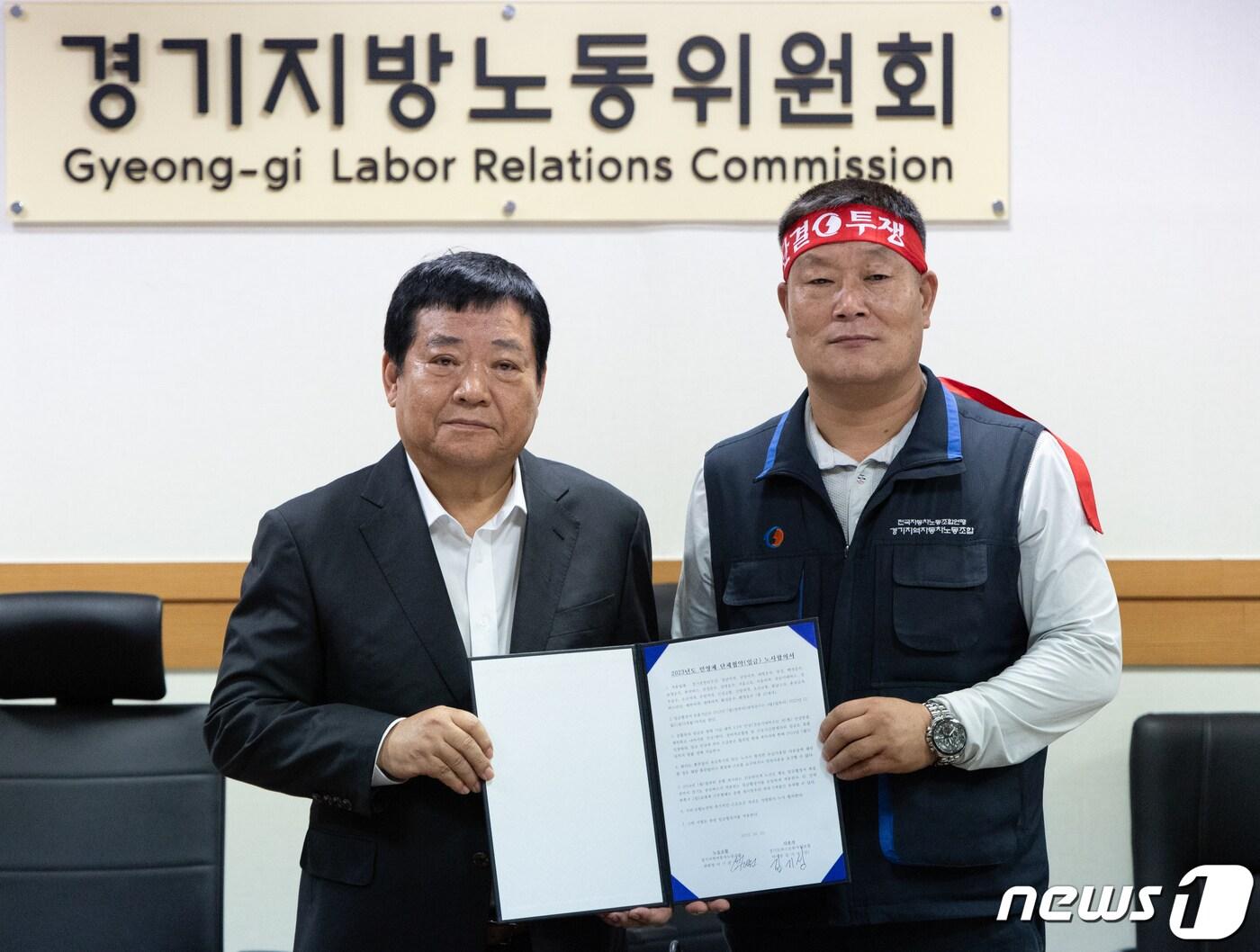 본문 이미지 - 김기성 경기도버스운송사업조합 이사장(왼쪽)과 이기천 경기도버스노조협의회 의장이 25일 오후 경기도 수원시 장안구 경기지방노동위원회에서 열린 경기지역자동차노동조합 노동쟁의 조정신청 사건에 대한 조정회의에서 협상이 타결한 후 합의서를 들고 기념 촬영하고 있다. 2023.10.25/뉴스1 ⓒ News1 이재명 기자