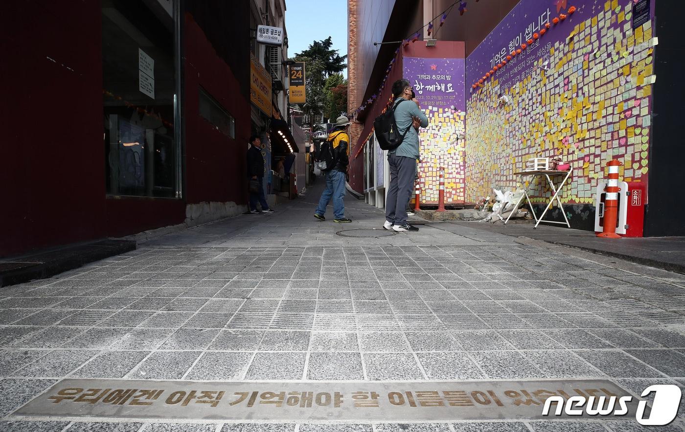본문 이미지 - 10.29 이태원 참사 1주기를 앞둔 27일 서울 용산구 이태원역 1번 출구 앞 골목 초입에 '우리에겐 아직 기억해야 할 이름들이 있습니다'라는 바닥명판이 새겨져 있다.  2023.10.27/뉴스1 ⓒ News1 박세연 기자