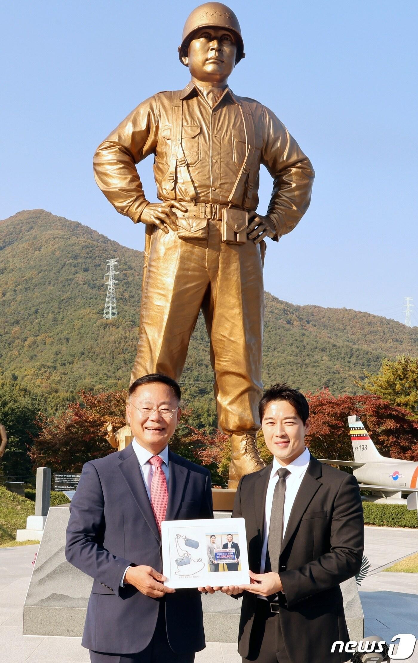본문 이미지 - 백선엽 장군 동상 앞에서 최영재 마스터가 29일 군번줄로 만든 액자를 김재욱 칠곡군수에게 전달하고 기념촬영을 하고 있다.(칠곡군 제공) 2023.10.30/뉴스1