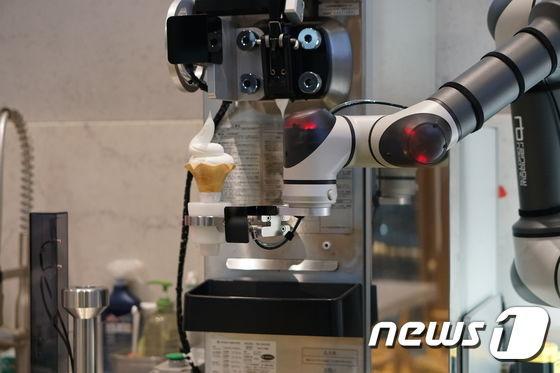 본문 이미지 - 차량 관리 플랫폼 카닥과 GS칼텍스가 함께 운영하는 경기도 고양시 카닥일산주유소 내 카페 '온더로드'에 아이스크림 서빙 협동로봇이 설치됐다. 이 협동로봇은 부품조립공정 등 제조업에 활용되던 레인보우로보틱스사의 협동로봇을 기반으로 만들어졌다. (카닥 제공) 2019.12.07/뉴스1