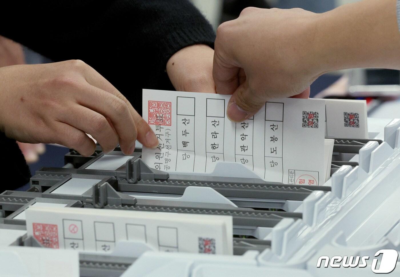 본문 이미지 - 13일 오후 서울 종로구 서울시선거관리위원회에서 열린 제22대 국회의원선거 대비 모의개표 실습에 참여한 각 구별 선관위 직원들이 투표지분류기에 투표지가 걸린 상황을 대처하고 있다. 2023.11.13/뉴스1 ⓒ News1 장수영 기자