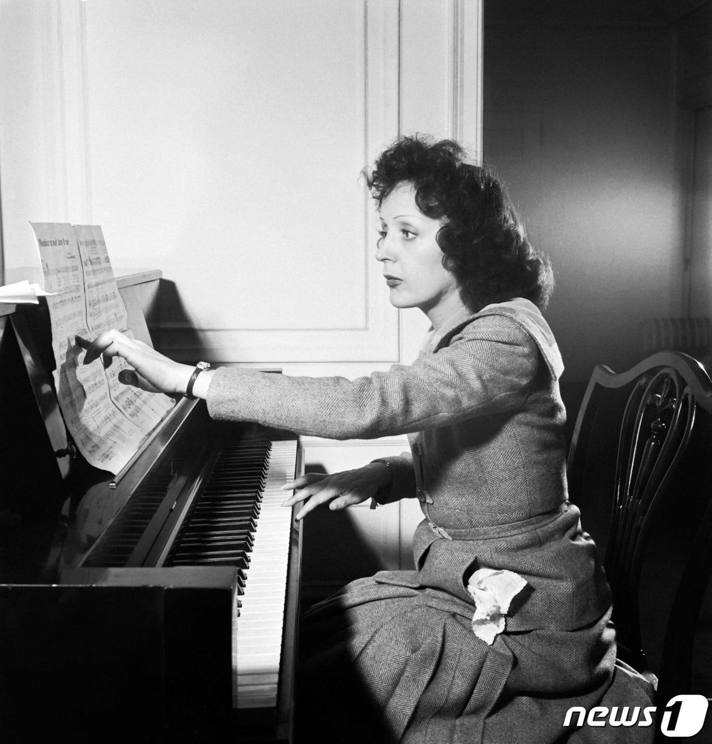 본문 이미지 - 프랑스의 대표적인 샹송 가수 에디트 피아프가 1946년 미국 뉴욕의 자택에서 피아노를 연주하고 있는 모습. ⓒ AFP=뉴스1 ⓒ News1 정지윤 기자