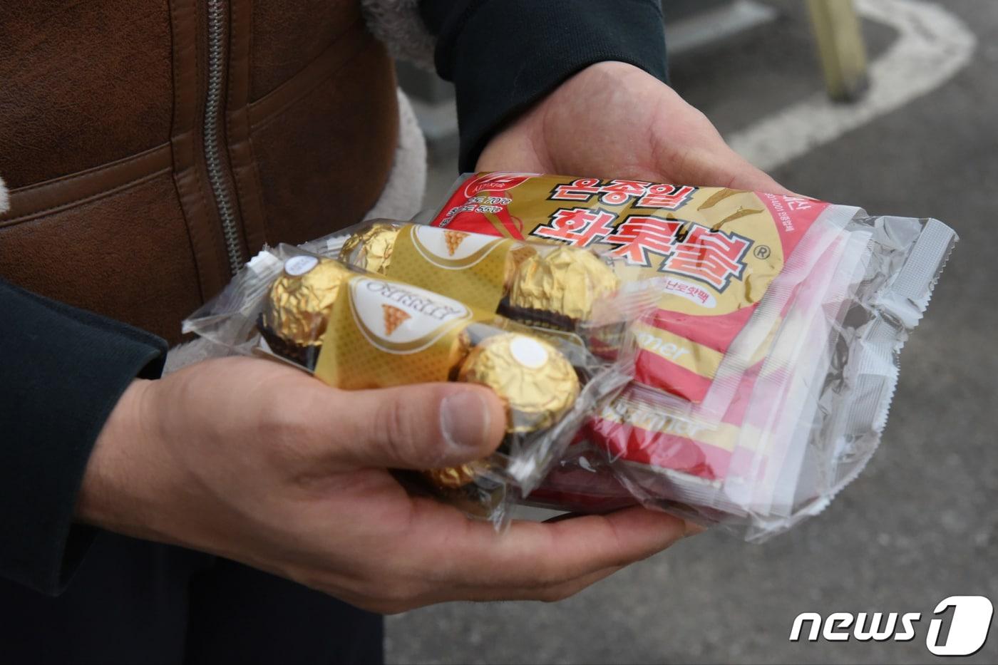 본문 이미지 - 2024학년도 대학수학능력시험일인 16일 오전 전남 순천매산고등학교 정문 앞에서 제일고 교사가 수험생들에게 전달해줄 핫팩과 초콜릿을 들고 있다.2023.11.16/뉴스1 ⓒ News1 김동수 기자