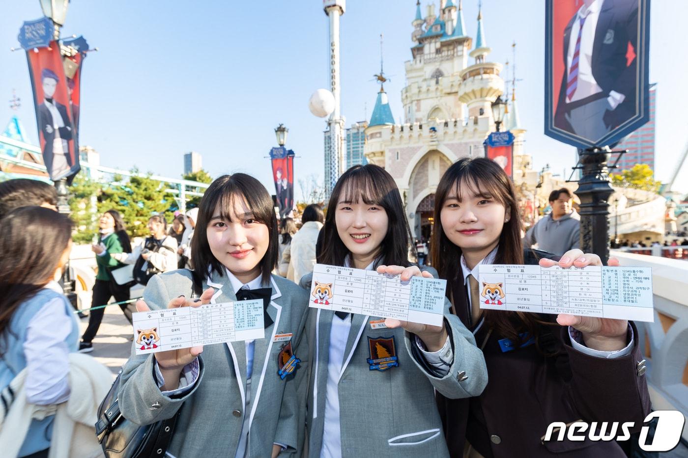 본문 이미지 - 롯데월드 어드벤처의 매직아일랜드에서 수험표 들고 인증샷 찍는 학생들(롯데월드 제공)