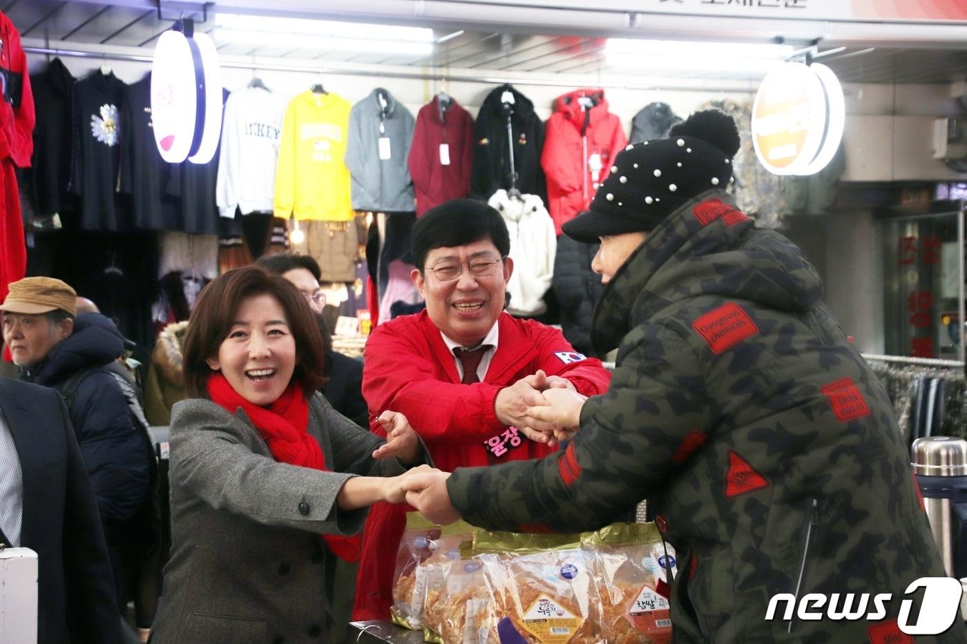 18일 대전 중앙시장을 방문한 국민의힘 나경원 전 원내대표&#40;왼쪽&#41;가 윤창현 동구 당협위원장과 함께 상인의 손을 맞잡고 인사를 나누고 있다. &#40;윤창현 의원실 제공&#41; /뉴스1