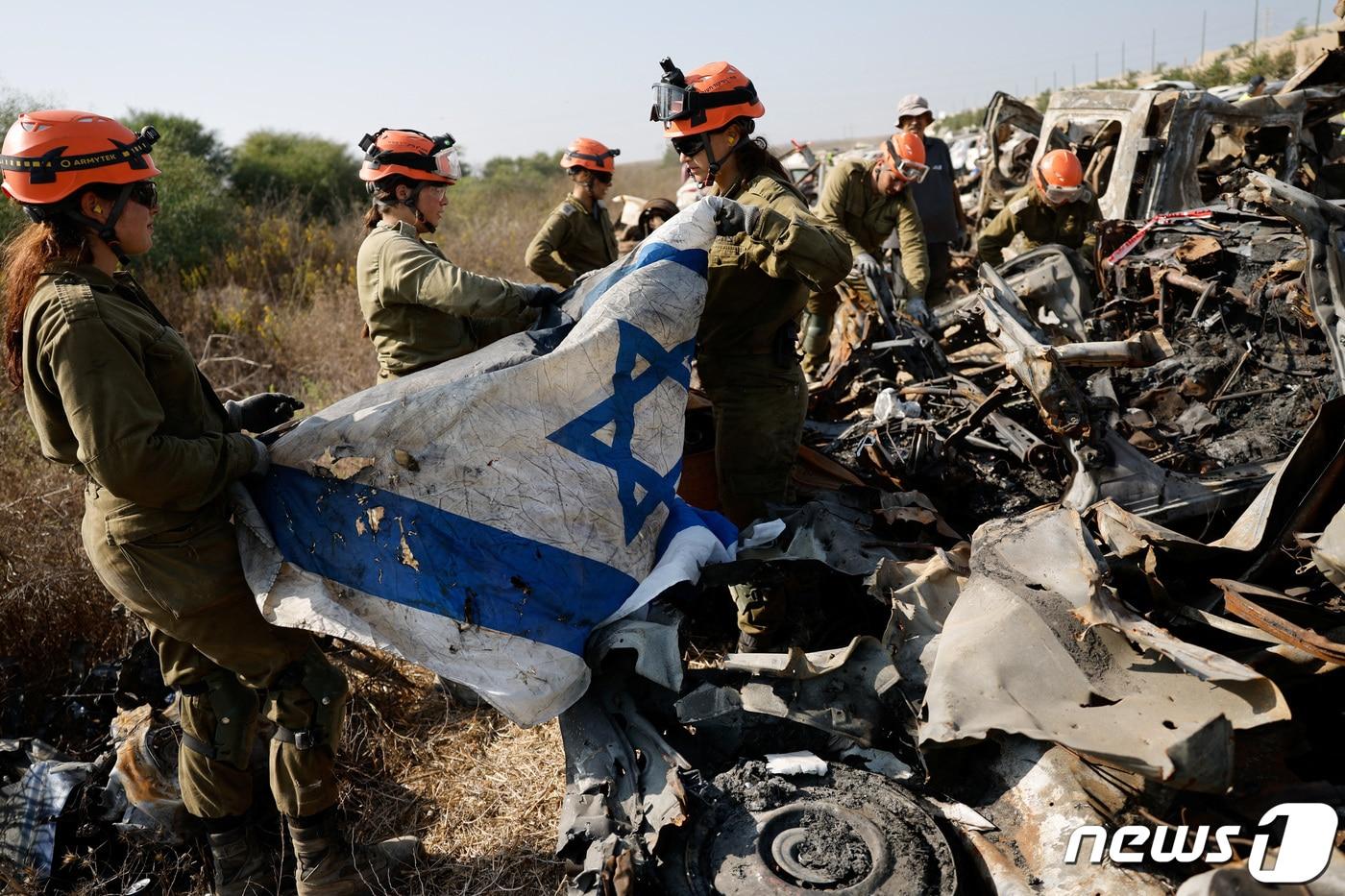 본문 이미지 - 지난 10월7일 가자지구에서 팔레스타인 무장 정파 하마스의 공격이 일어난 후 사령부 소속 이스라엘 군인들이 이스라엘 네티보트의 파손된 차량에서 유해와 기타 증거물을 수색하다가 이스라엘 국기를 발견해 회수하고 있다. 2023.11.02 ⓒ 로이터=뉴스1 ⓒ News1 정지윤 기자
