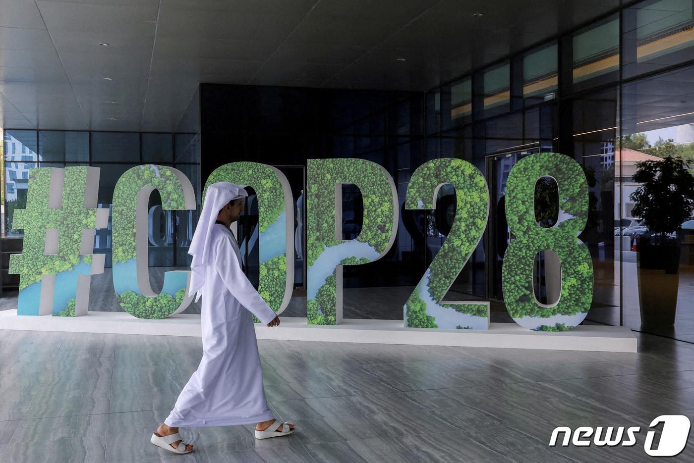 본문 이미지 - 제28차 유엔기후변화협약 당사국총회(COP28)가 열리는 아랍에미리트(UAE) 아부다비에서 행인이 COP28을 홍보하는 게시물 앞으로 지나가고 있다. 2023.10.01/ ⓒ 로이터=뉴스1 ⓒ News1 박재하 기자