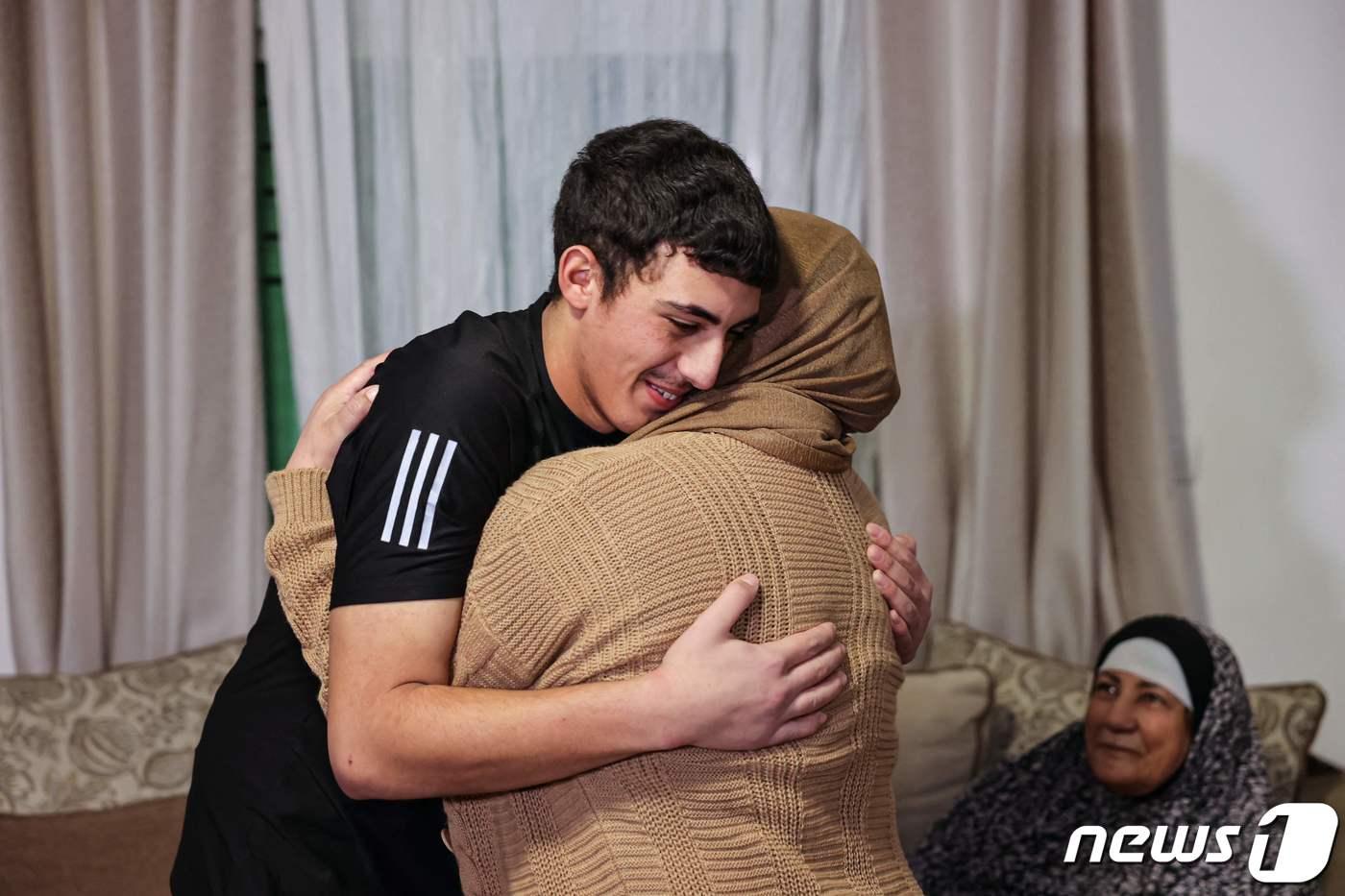 본문 이미지 - 28일(현지시간) 이스라엘 감옥에서 석방된 팔레스타인인 무함마드 아부 알-후무스가 예루살렘 동부의 집으로 돌아와 어머니를 안아주고 있다. 2023.11.28 ⓒ AFP=뉴스1 ⓒ News1 정지윤 기자