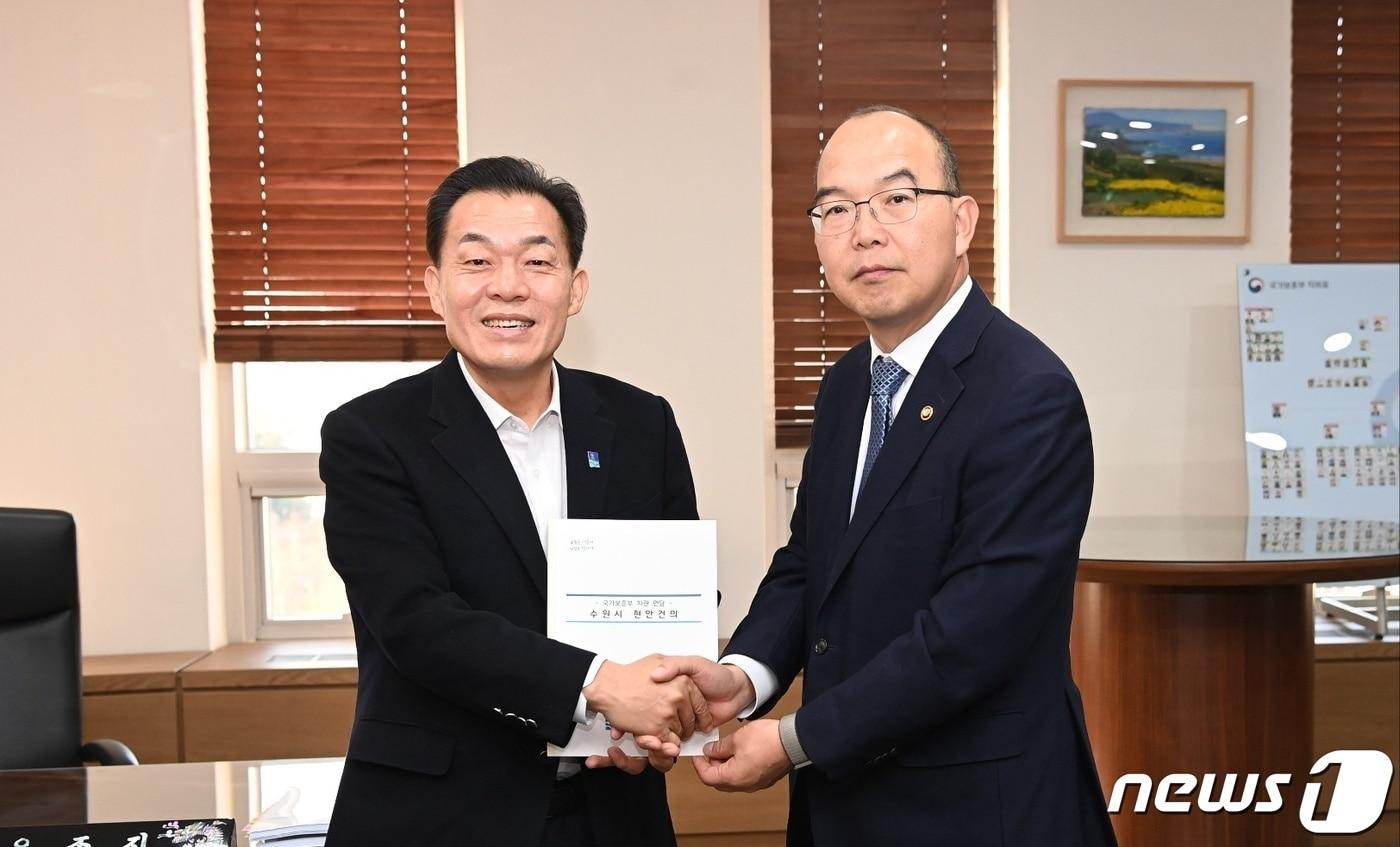 본문 이미지 - 이재준 수원시장(왼쪽)이 윤종진 국가보훈부 차관에게 건의문을 전달하고 있다.(수원시 제공)