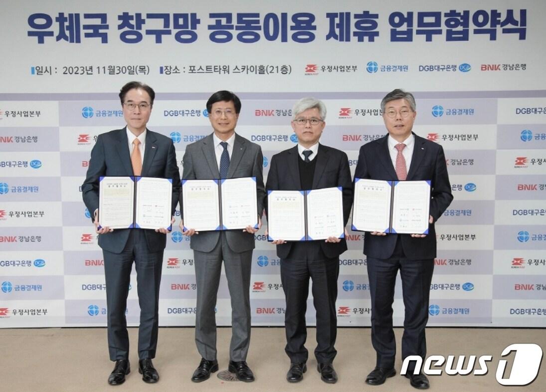 본문 이미지 - 30일 황병우 DGB대구은행장(오른쪽)이 조해근 우정사업본부장(오른쪽 두번째)과 '우체국 창구망 공동이용 제휴 업무협약'을 체결한 뒤 협약서를 펼쳐 보이고 있다.(대구은행 제공)