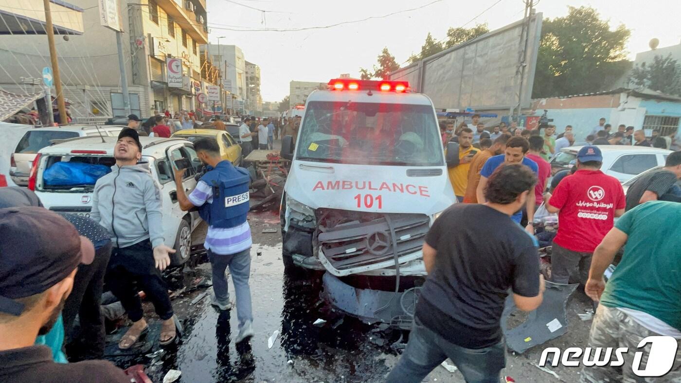 본문 이미지 - 3일(현지시간) 팔레스타인 가자 시티 시파 병원 입구에서 구급차 행렬이 이스라엘에 피격된 후 팔레스타인 사람들이 피해 상황을 확인하고 있다. 2023.11.07 ⓒ 로이터=뉴스1 ⓒ News1 정지윤 기자