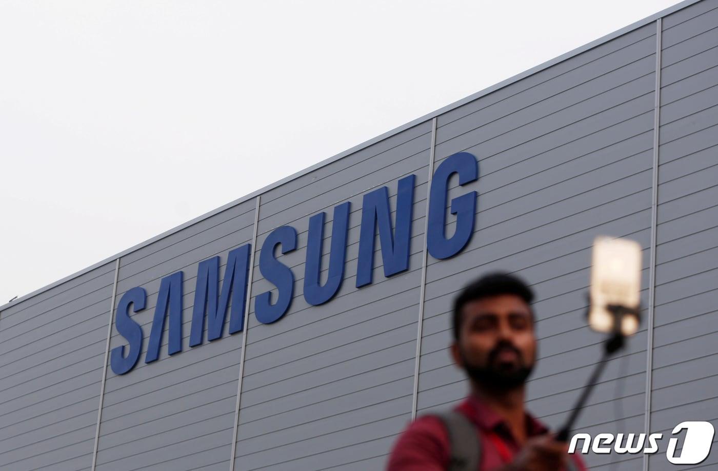 인도 노이다에 위치한 삼성 스마트폰 제조 공장 앞에서 한 남성이 휴대폰으로 사진을 촬영하고 있는 모습. 2018.07.09. ⓒ 로이터=뉴스1 ⓒ News1 정윤영 기자