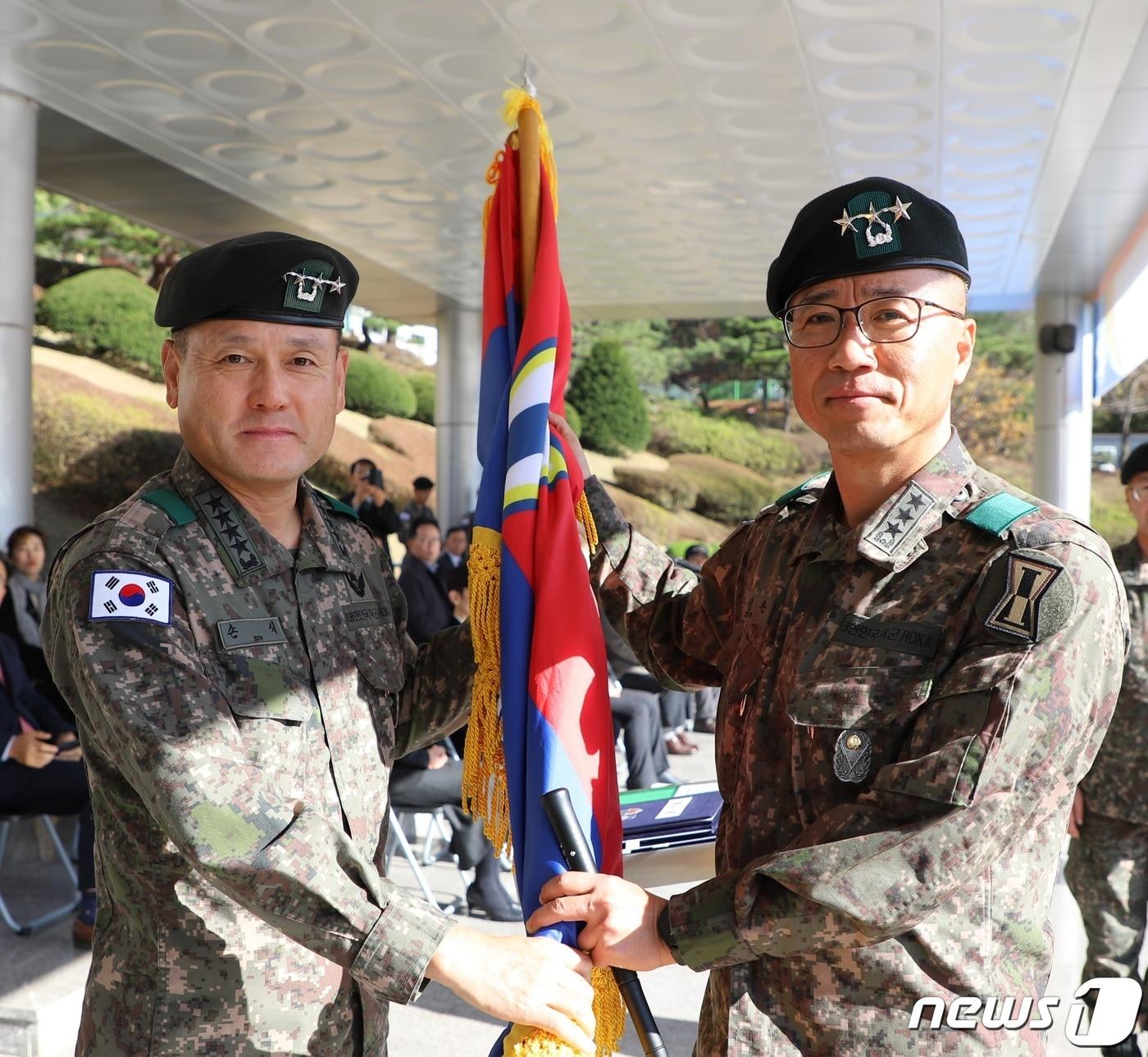 본문 이미지 - 8일 육군 제1군단사령부에서 열린 57대 군단장 취임식에서 손식 지상작전사령관(왼쪽)이 주성운 신임 군단장에게 부대기를 전달하고 있다. (1군단 제공)
