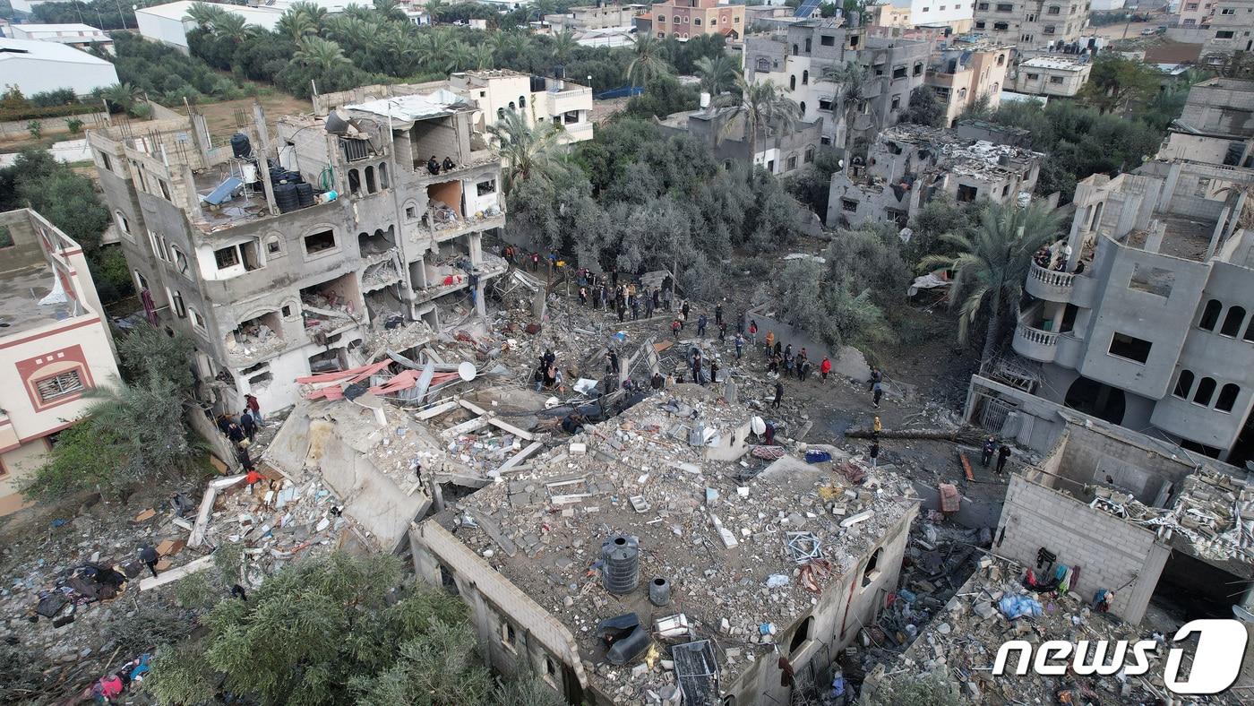 본문 이미지 - 25일(현지시간) 가자지구 중부의 알마가지 난민촌에 이스라엘의 공습이 내린 가운데 사람들이 폭격으로 무너진 주택 주변에 서있다. 2023.12.25 ⓒ 로이터=뉴스1 ⓒ News1 정지윤 기자