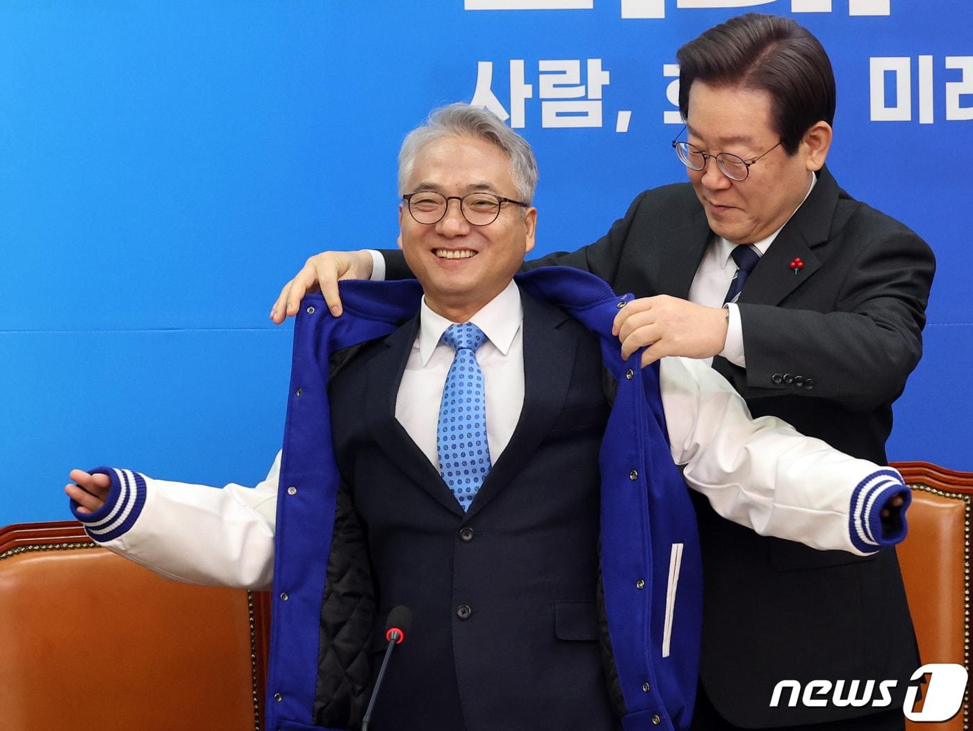 본문 이미지 - 이재명 더불어민주당 대표가 27일 오전 서울 여의도 국회에서 열린 민주당 4·5호 인재영입식에서 인재영입 4호 박선원 전 국가정보원 제1차장에게 당 점퍼를 입혀주고 있다. 2023.12.27/뉴스1 ⓒ News1 황기선 기자