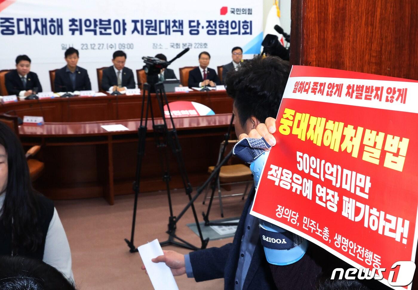 고 김용균씨 어머니 김미숙씨가 27일 서울 여의도 국회에서 열린 중대재해 취약분야 지원대책 관련 당정협의회 회장 앞에서 '중대재해처벌법 적용유예연장 폐기' 손 피켓을 들고 있다. 2023.12.27/뉴스1 ⓒ News1 송원영 기자