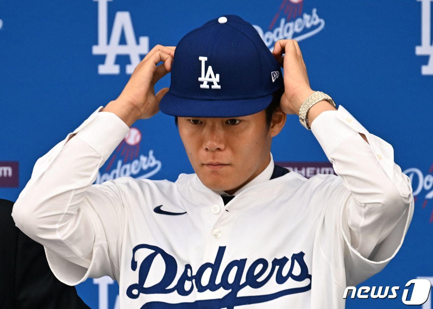 본문 이미지 - 일본인 투수 야마모토 요시노부가 27일(현지시간) 역대 MLB 투수 최고 보장액인 12년 3억2500만 달러를 받고 캘리포니아주 로스앤젤레스 다저스타디움에서 열린 입단식서 다저스 유니폼과 모자를 착용하고 있다. 2023.12.28 ⓒ AFP=뉴스1 ⓒ News1 우동명 기자