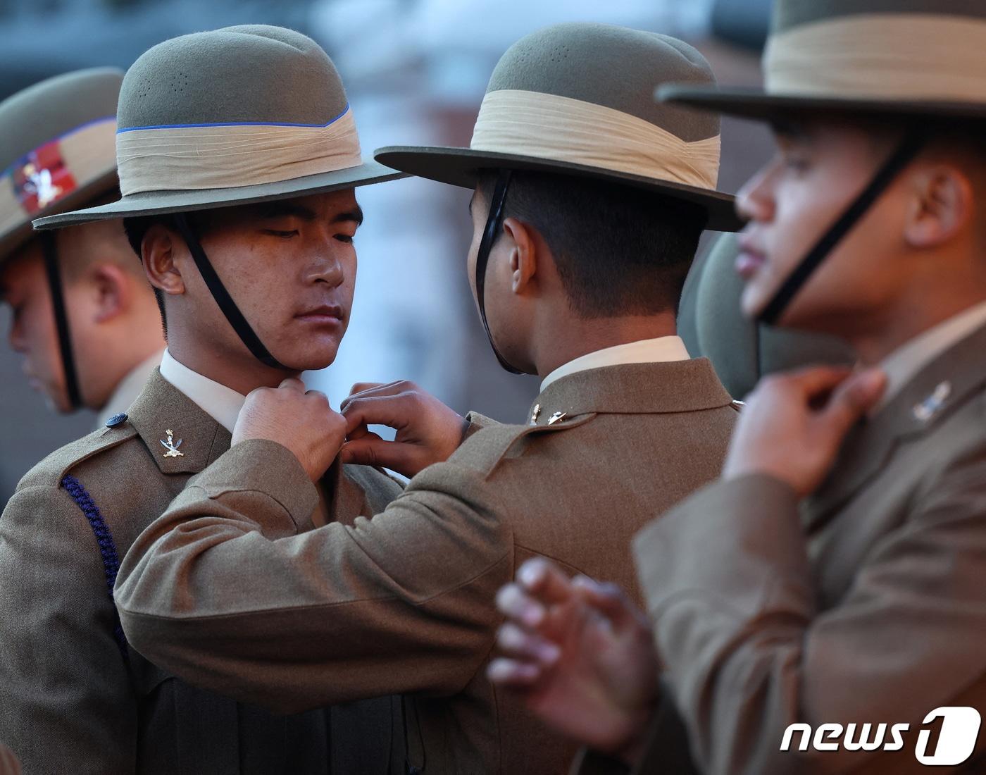 본문 이미지 - 지난달 23일(현지시간) 영국 런던 외곽의 리치먼드 인근에서 네팔의 구르카 용병들이 훈련소 수료식을 앞두고 서로의 옷매무새를 정리해주는 모습이다. 2023.11.23. ⓒ 로이터=뉴스1 ⓒ News1 김성식 기자
