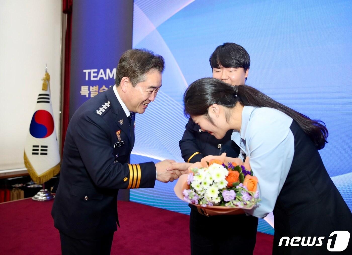본문 이미지 - 윤희근 경찰청장(왼쪽)이 7일 서울 서대문구 경찰청에서 열린 '팀 특진 임용식'에서 충남청 반부패경제범죄수사대 특진자 최석용 경사(가운데)의 아내와 축하 인사를 나누는 모습. (자료=경찰청 제공)