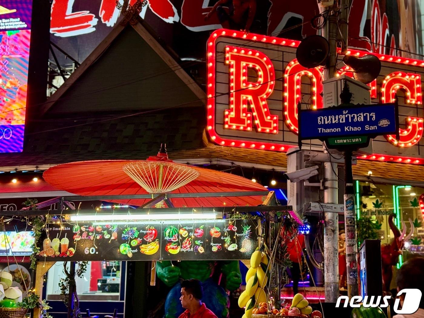 본문 이미지 - 카오산로드 초입에 과일 노점상이 보인다. 전봇대 위에 카오산로드라고 적힌 간판이 있다. ⓒ News1 이민주 기자