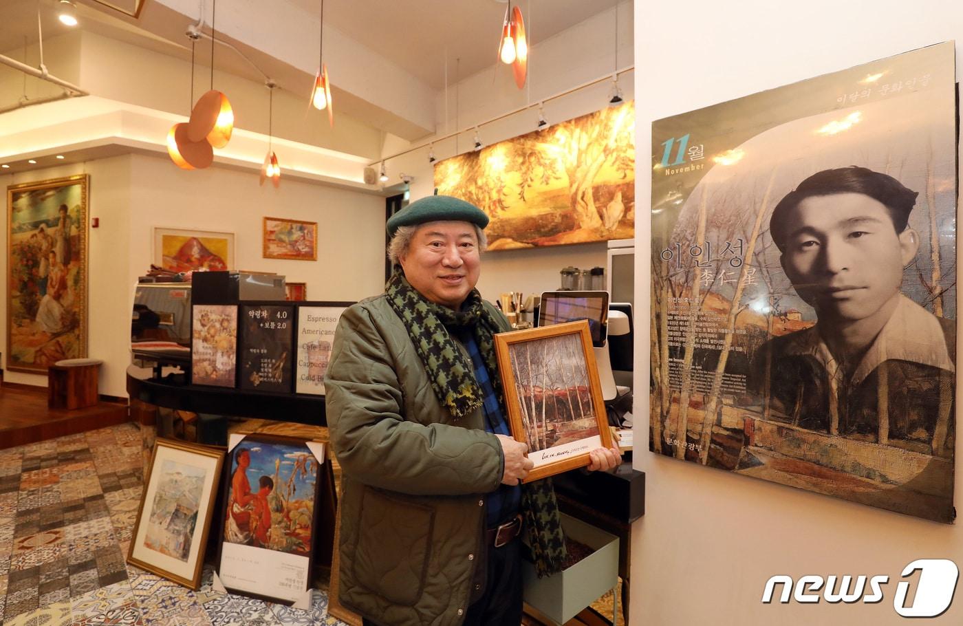 '천재화가 이인성(1912~1950)'의 아들 이채원 이인성기념사업회 회장이 아버지 사진 옆에서 포즈를 취했다. 손에 든 그림은 이인성의 '겨울 어느날'. 이인성이 신촌 이화여대 강사 시절 북아현 굴레방다리 인근 풍경 그린 것이라고 했다.