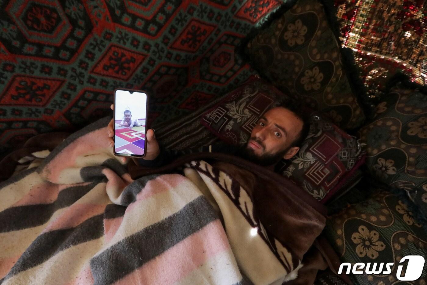 8일(현지시간) 시리아 잔다리스 마을에서 발생한 대지진의 생존자 압둘라만 알리 알마무드. 아내와 딸을 여읜 알마무드가 핸드폰으로 숨진 딸의 사진을 보여주고 있다. ⓒ 로이터=뉴스1 ⓒ News1 권진영 기자