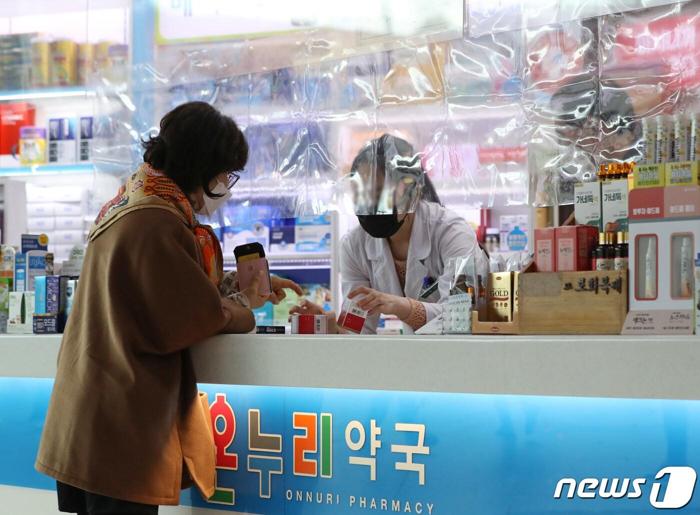 본문 이미지 - 서울역 내 약국에서 마스크를 착용한 시민이 의약품을 구매하고 있다.  2023.3.15/뉴스1 ⓒ News1 장수영 기자