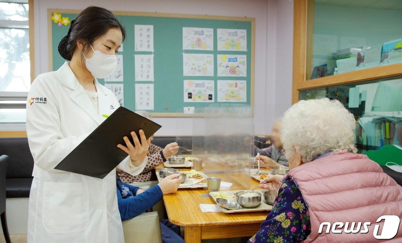 본문 이미지 - 아워홈 영양사가 서울 마포구에 위치한 한서데이케어센터에서 ‘인지기능개선 관리 식단’을 시설 이용 어르신에게 소개하고 있다.(아워홈 제공) 