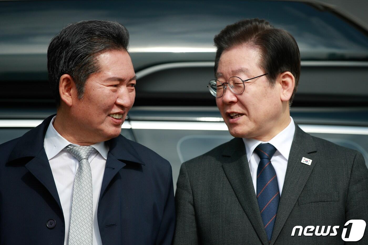 본문 이미지 - 이재명 더불어민주당 대표(오른쪽)가 지난 22일 서울 여의도 국회에서 대일굴종외교 규탄 태극기달기 운동 행사의 일환으로 차량에 태극마크와 '역사를 팔아서 미래를 살 수는 없습니다'라고 적힌 스티커를 부착하기 전 정청래 최고위원과 대화하고 있다. ⓒ 뉴스1 안은나 기자