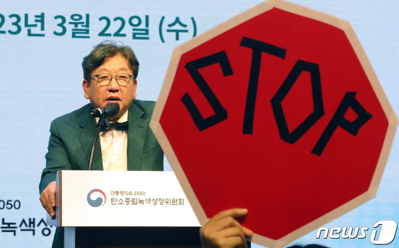 김상협 탄소중립녹색성장위원장이 22일 서울 강남구 한국과학기술회관에서 열린 국가탄소중립 녹색성장 기본계획 수립 등에 대한 공청회에서 발언하고 있는 가운데 환경단체 회원들이 기본계획 철회를 촉구하며 피켓 시위를 하고 있다. 2023.3.22/뉴스1 ⓒ News1 박세연 기자